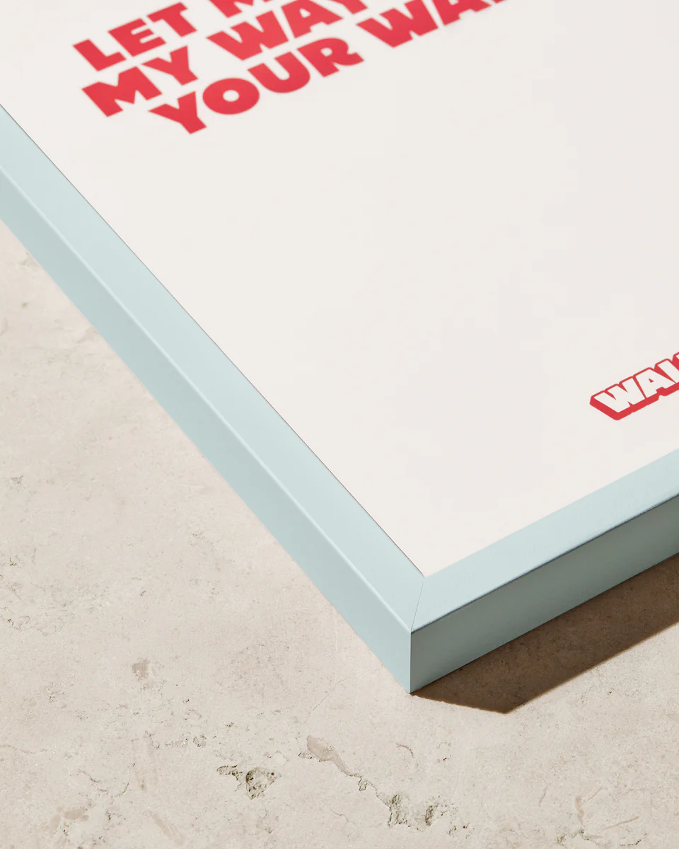 A close-up highlights the Frame Pastel Blues stylish pop of color in a corner on a textured surface. Partially visible red text reads LET MY WA... at the top and YOUR WA... at the bottom, with a partial red logo showing WA... in the lower right.