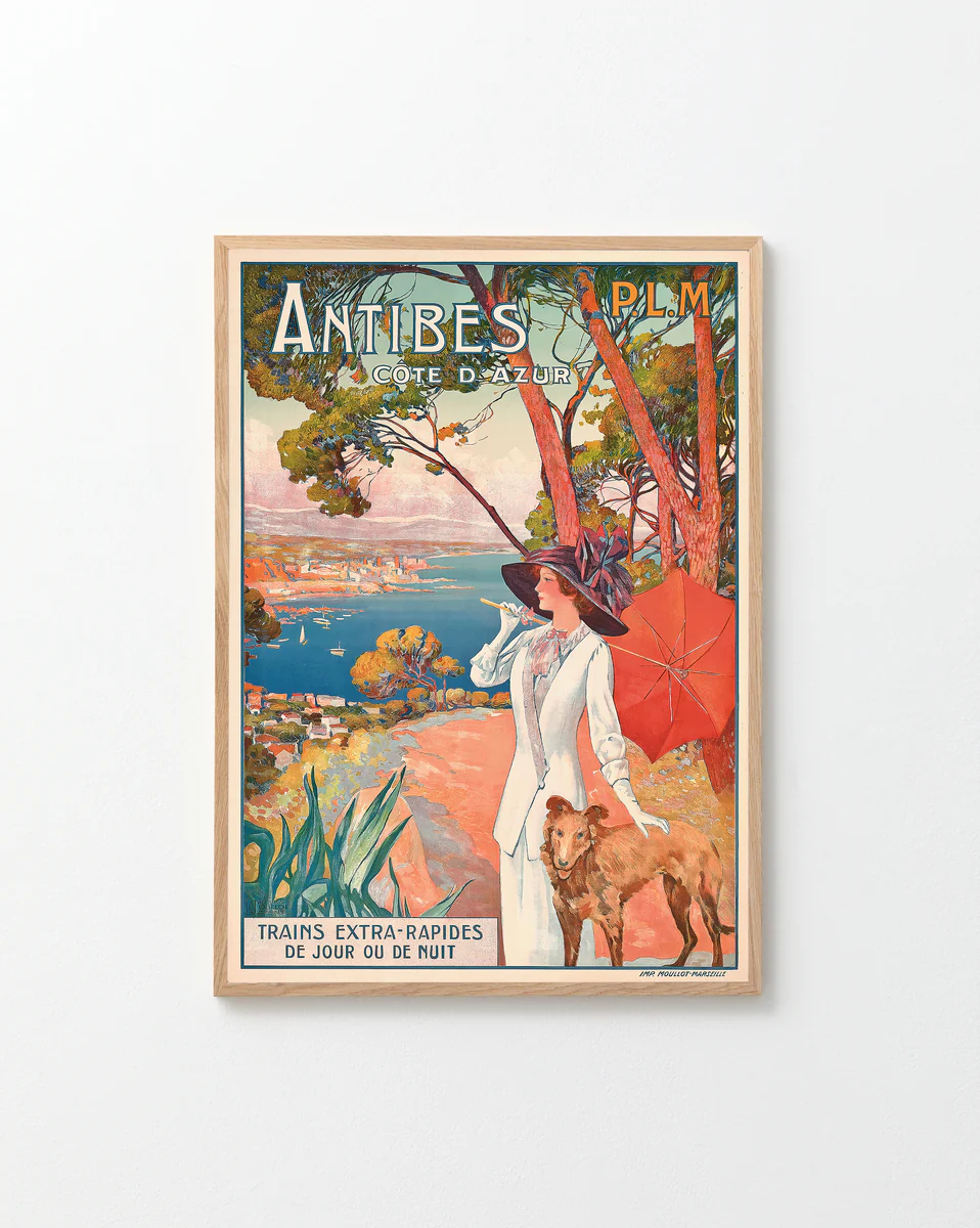 The Antibes Cote dAzur Poster showcases vintage wall art of a woman in white walking a dog under a red umbrella, with coastal views and pine trees. Perfect for French Riviera fans, it notes express trains available day or night.