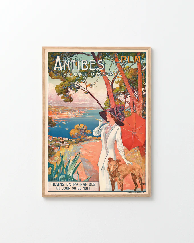 The Antibes Cote dAzur Poster showcases vintage wall art of a woman in white walking a dog under a red umbrella, with coastal views and pine trees. Perfect for French Riviera fans, it notes express trains available day or night.