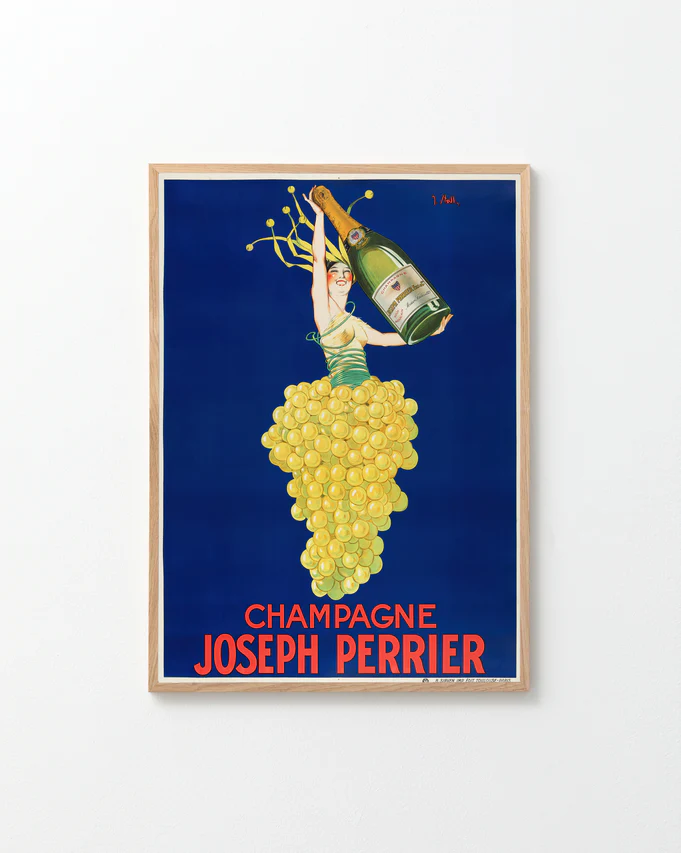 The Champagne Joseph Perrier Poster features a vintage Art Deco design with a woman in a grape-cluster dress holding a Champagne bottle against a deep blue background. Bold red letters at the bottom read Champagne Joseph Perrier, all set within an elegant light wood frame.