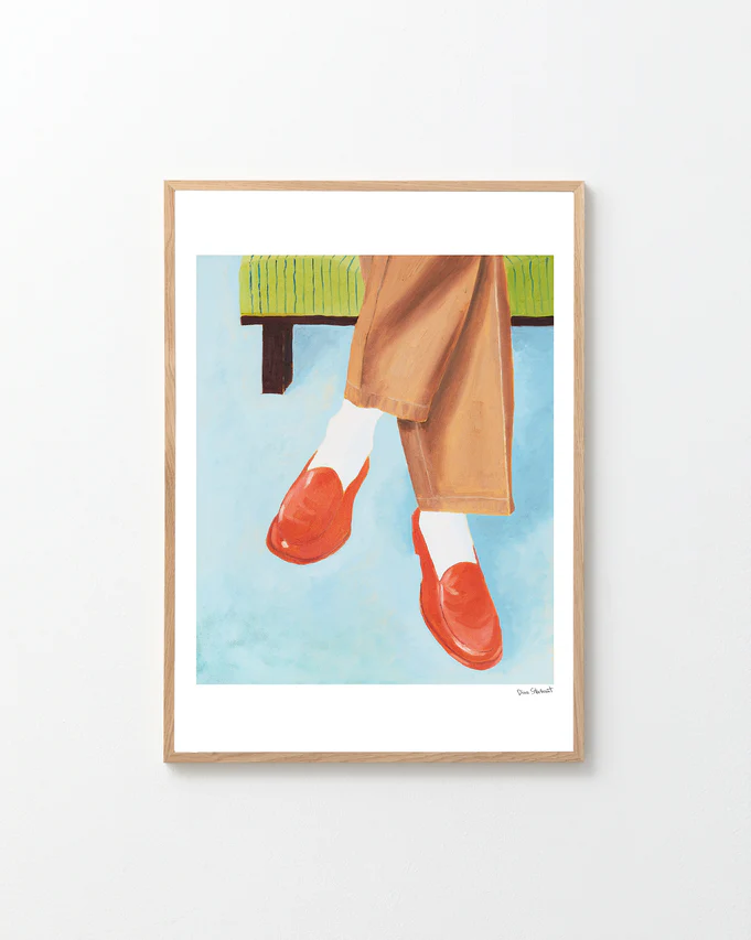 Framed artwork of red shoes, beige pants, and white socks against a blue background.