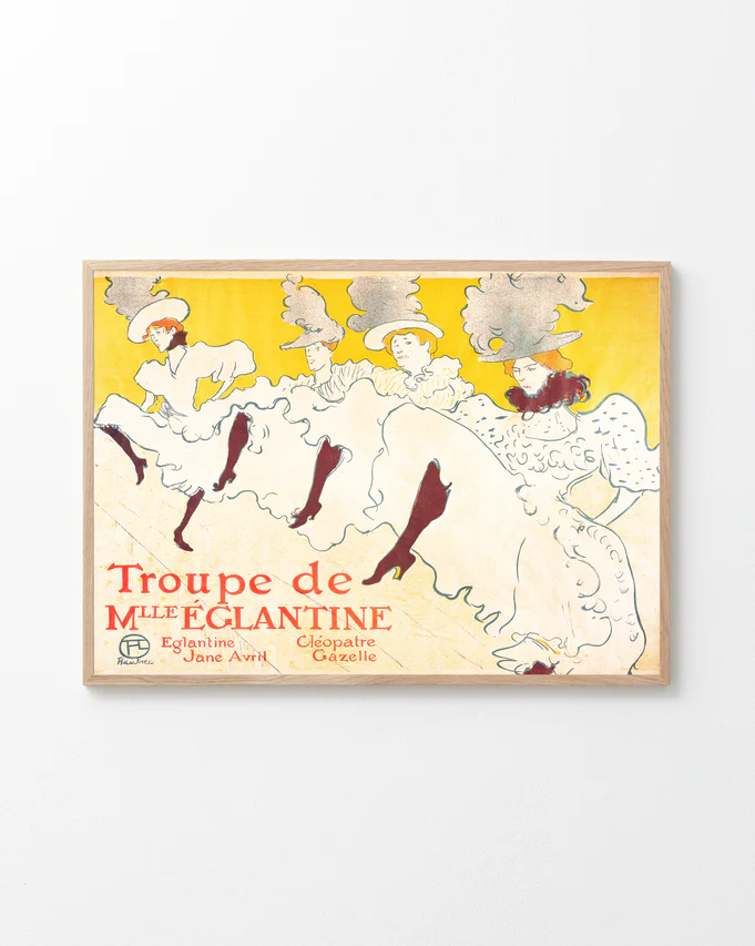 A framed poster titled La Troupe de Mademoiselle Eglantine by Henri de Toulouse-Lautrec features elegant dancers in flowing white dresses and elaborate hats against a bright yellow background, including performers Eglantine, Jane Avril, and Cléopâtre, evoking the Belle Époque era.
