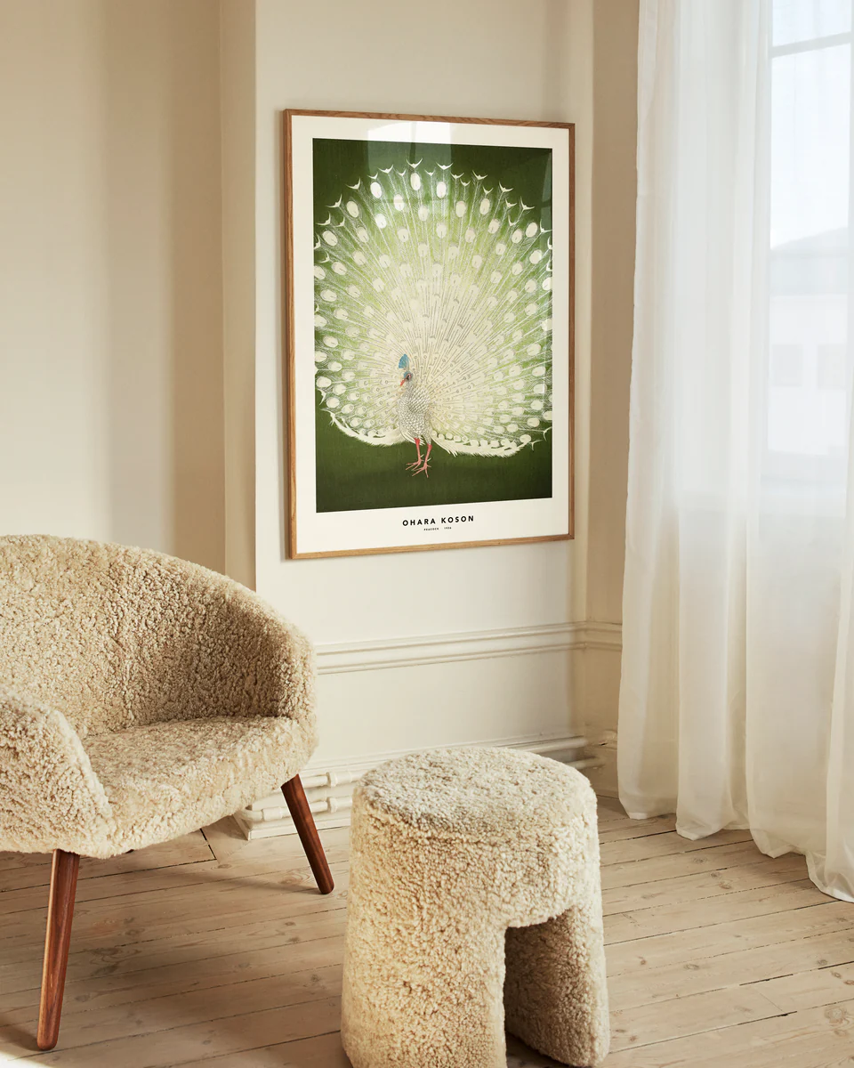 Furry chair and stool in a room with a framed artwork of a peacock on the wall.