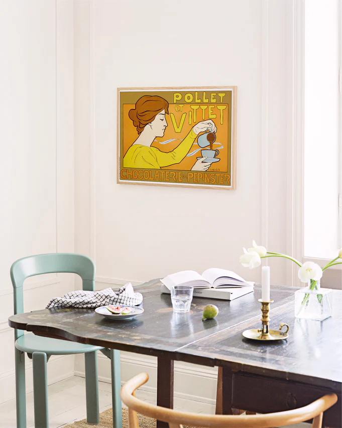 Dining room with a table and chairs, featuring a vintage-style poster on the wall.