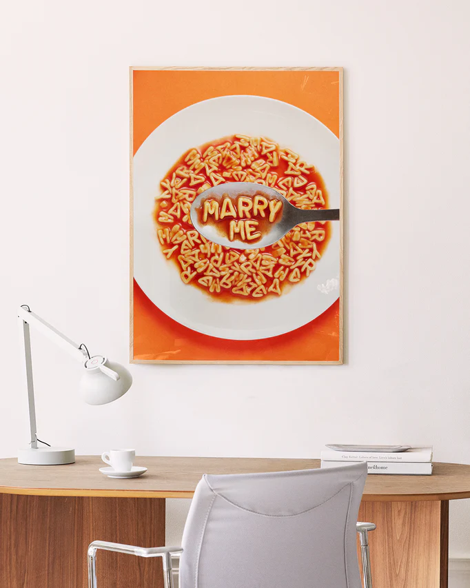 Poster "Marry Me" in oak frame above a desk