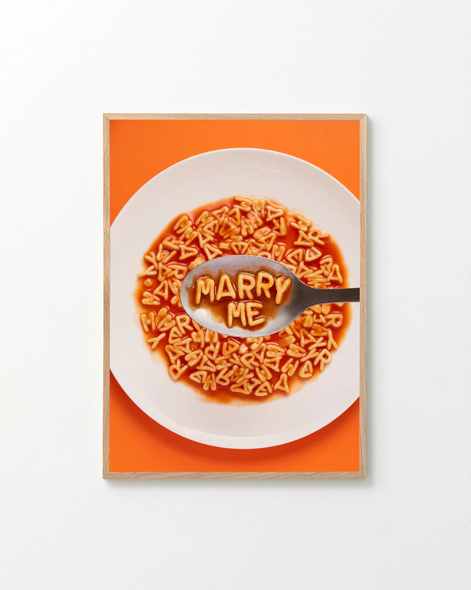 Poster "Marry Me" in a oak frame against a white background