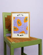 Poster Papaya No2 in an oak frame placed on a green chair against a purple background.