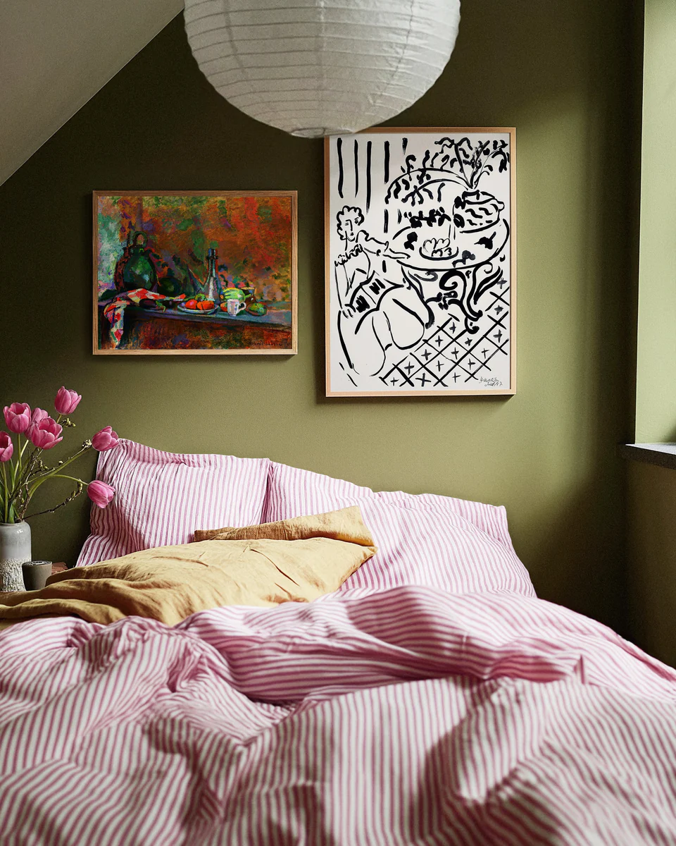 Bedroom with green walls, pink bedding, and framed artwork.