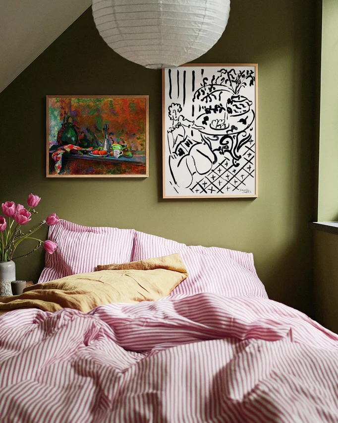 Bedroom with green walls, pink bedding, and framed artwork.