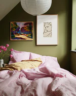 Bedroom with green walls, pink striped bedding, and framed artwork.