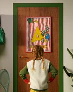 Pippi Longstocking poster featuring the letter A hanging on a door, with a child curiously looking at the artwork.