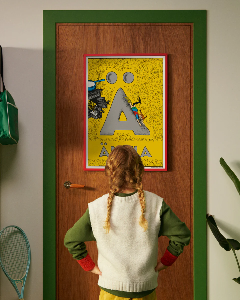 Pippi Longstocking personalised poster featuring the letter Ä hanging on a door, with a child curiously looking at the artwork.
