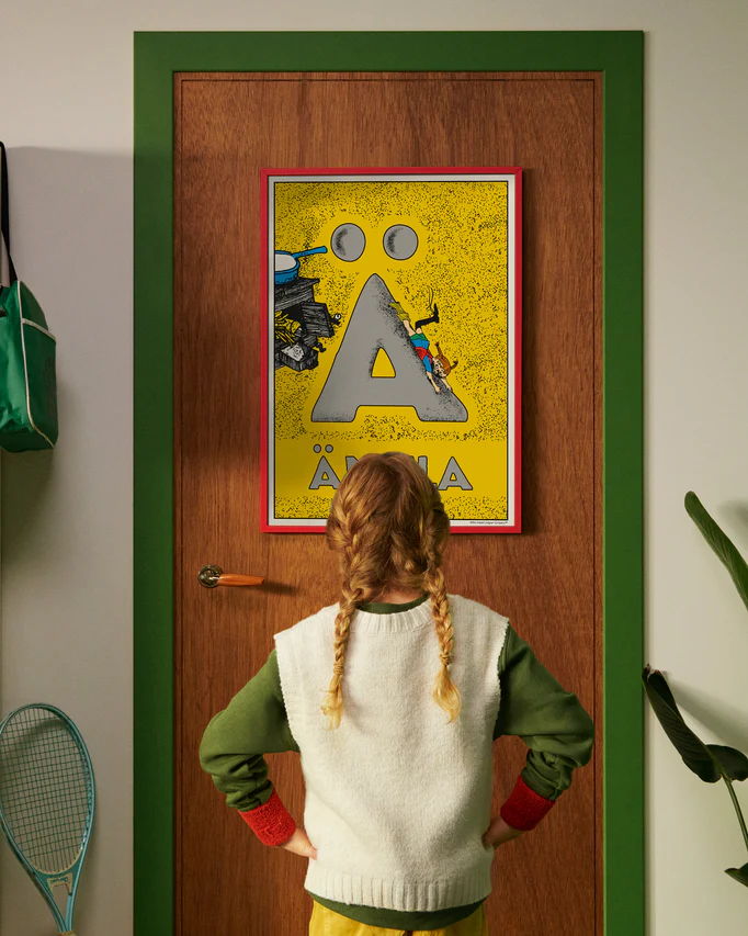 Pippi Longstocking personalised poster featuring the letter Ä hanging on a door, with a child curiously looking at the artwork.
