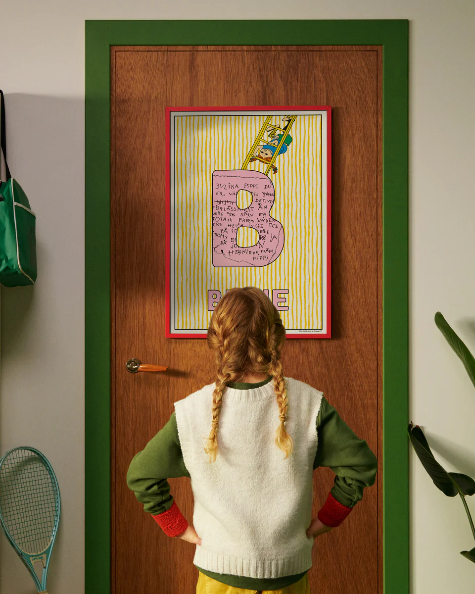 Pippi Longstocking personalised poster featuring the letter B hanging on a door, with a child curiously looking at the artwork.