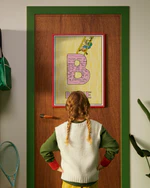 Pippi Longstocking personalised poster featuring the letter B hanging on a door, with a child curiously looking at the artwork.