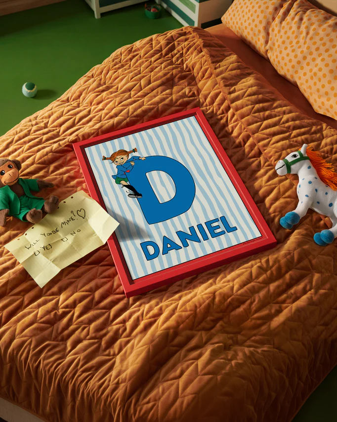 Pippi Longstocking name poster with the letter D and the name Daniel, placed on a neatly made bed in a bright kids’ room.