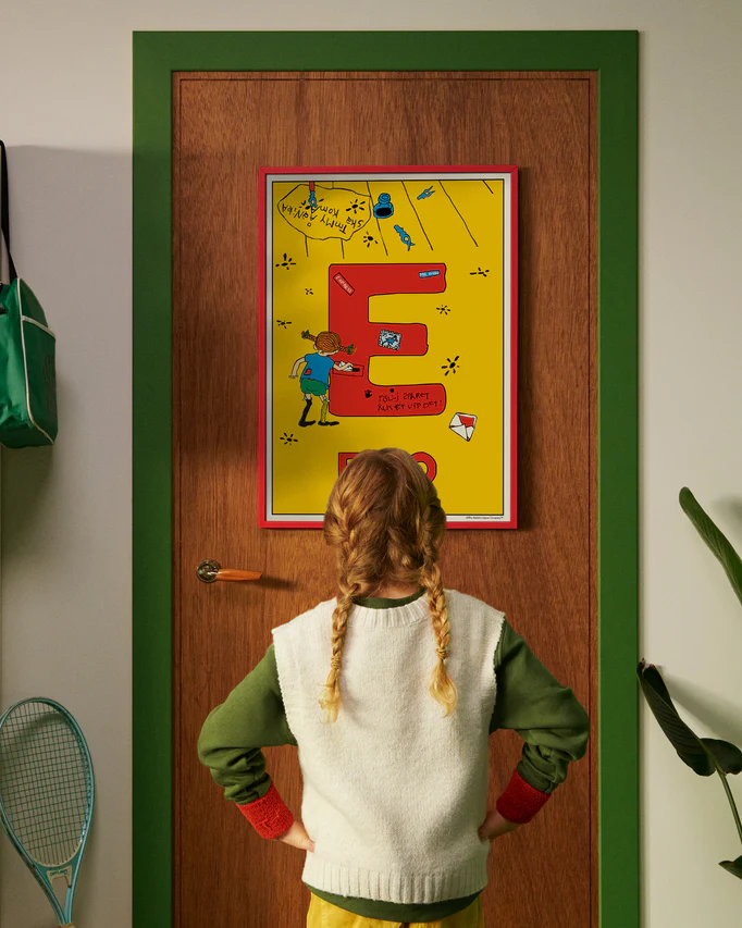 Pippi Longstocking personalised poster featuring the letter E hanging on a door, with a child curiously looking at the artwork.