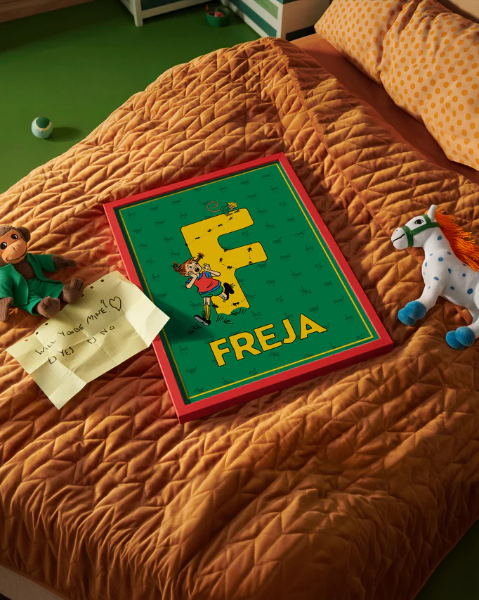 Pippi Longstocking name poster with the letter F and the name Freja placed on a neatly made bed in a bright kids’ room.
