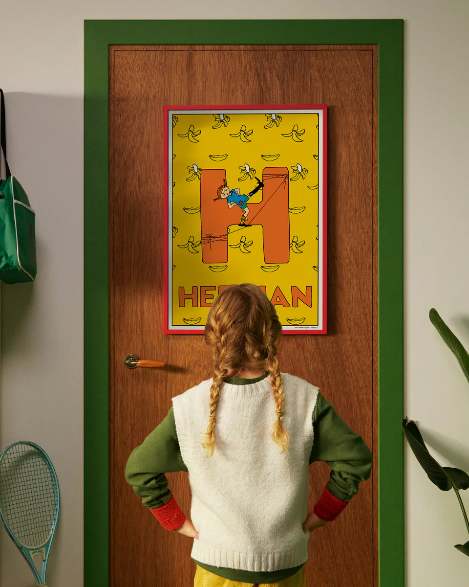 Pippi Longstocking personalised poster featuring the letter H hanging on a door, with a child curiously looking at the artwork.