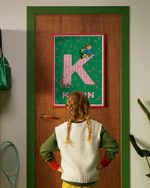 Pippi Longstocking personalised poster featuring the letter K hanging on a door, with a child curiously looking at the artwork.