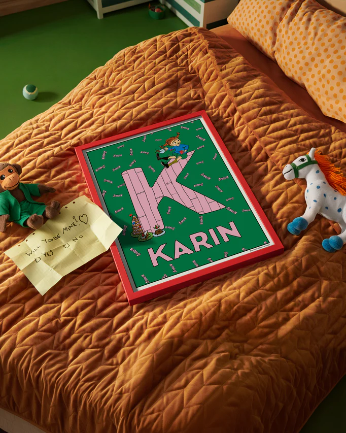 Pippi Longstocking name poster with the letter K and the name Karin, placed on a neatly made bed in a bright kids’ room.
