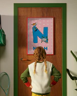 Pippi Longstocking personalised poster featuring the letter N hanging on a door, with a child curiously looking at the artwork.