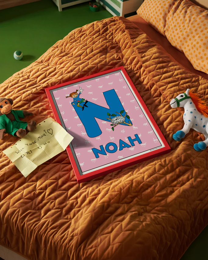 Pippi Longstocking name poster with the letter N and the name Noah, placed on a neatly made bed in a bright kids’ room.