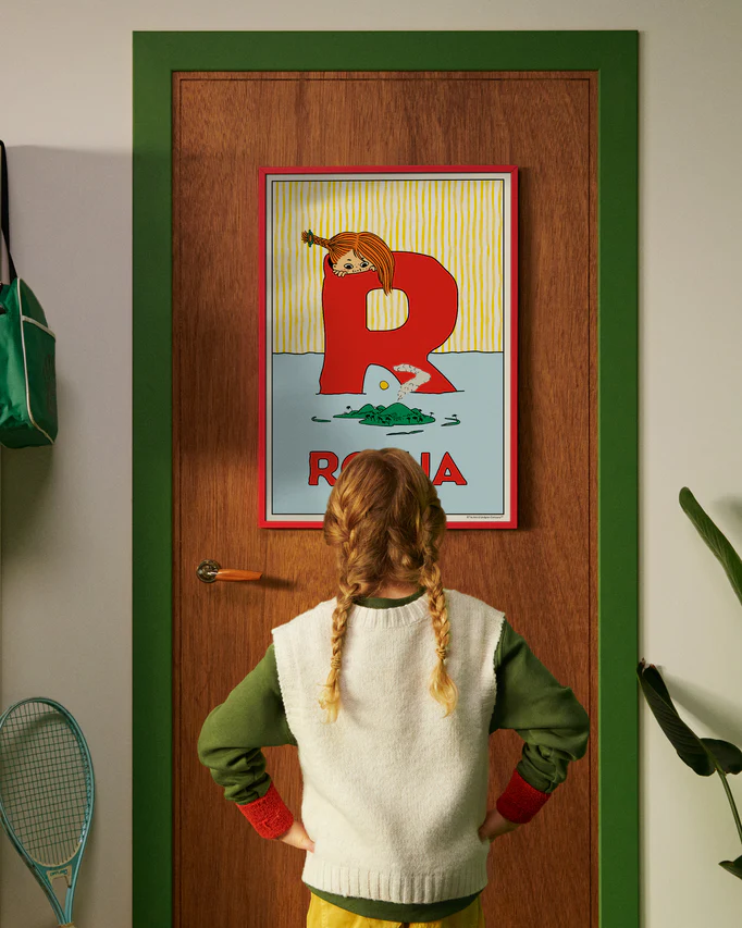 Pippi Longstocking personalised poster featuring the letter R hanging on a door, with a child curiously looking at the artwork.