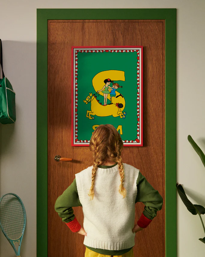 Pippi Longstocking personalised poster featuring the letter S hanging on a door, with a child curiously looking at the artwork.