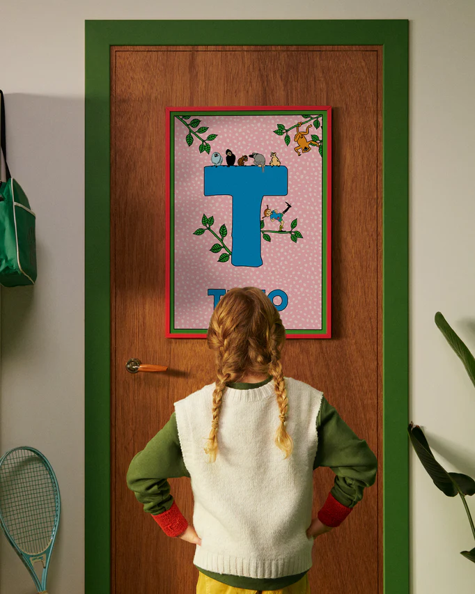 Pippi Longstocking personalised poster featuring the letter T hanging on a door, with a child curiously looking at the artwork.