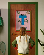 Pippi Longstocking personalised poster featuring the letter T hanging on a door, with a child curiously looking at the artwork.