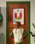 Pippi Longstocking personalised poster featuring the letter U hanging on a door, with a child curiously looking at the artwork.