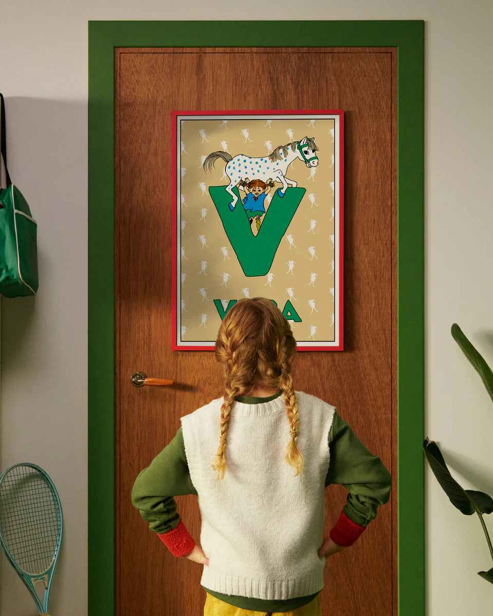 Pippi Longstocking personalised poster featuring the letter V hanging on a door, with a child curiously looking at the artwork.