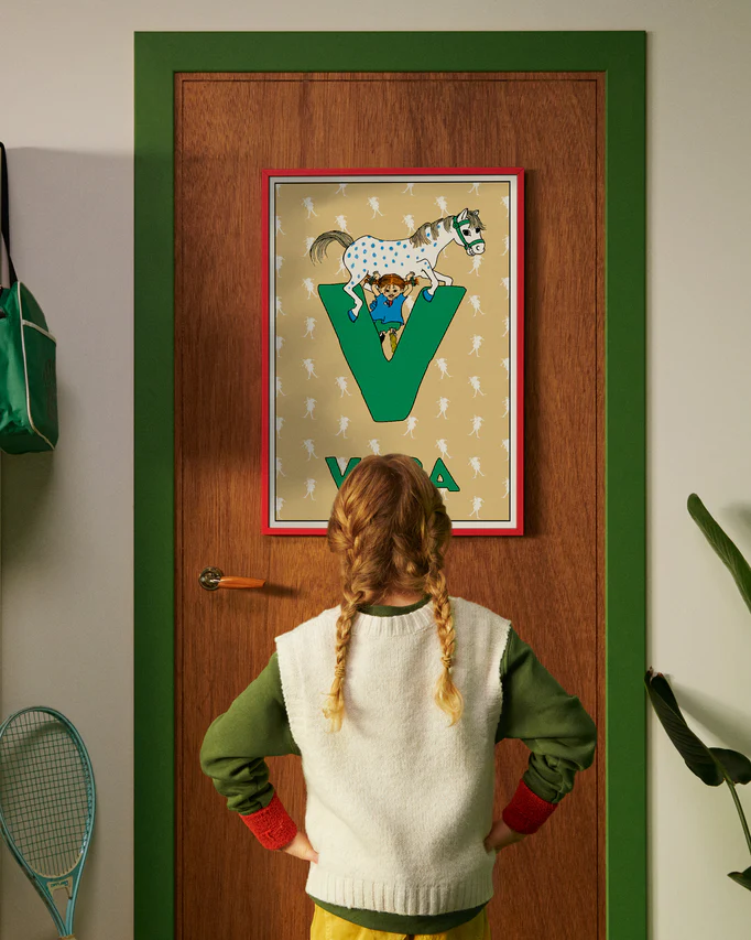 Pippi Longstocking personalised poster featuring the letter V hanging on a door, with a child curiously looking at the artwork.