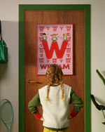Pippi Longstocking personalised poster featuring the letter W hanging on a door, with a child curiously looking at the artwork.