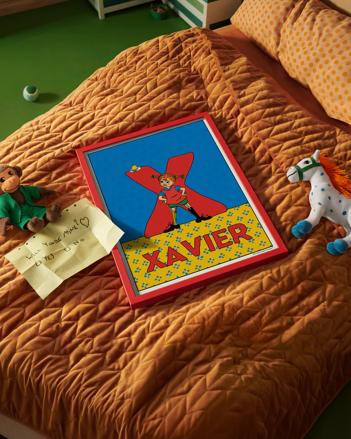 Pippi Longstocking name poster with the letter X and the name Xavier, placed on a neatly made bed in a bright kids’ room.