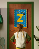 Pippi Longstocking personalised poster featuring the letter Z hanging on a door, with a child curiously looking at the artwork.