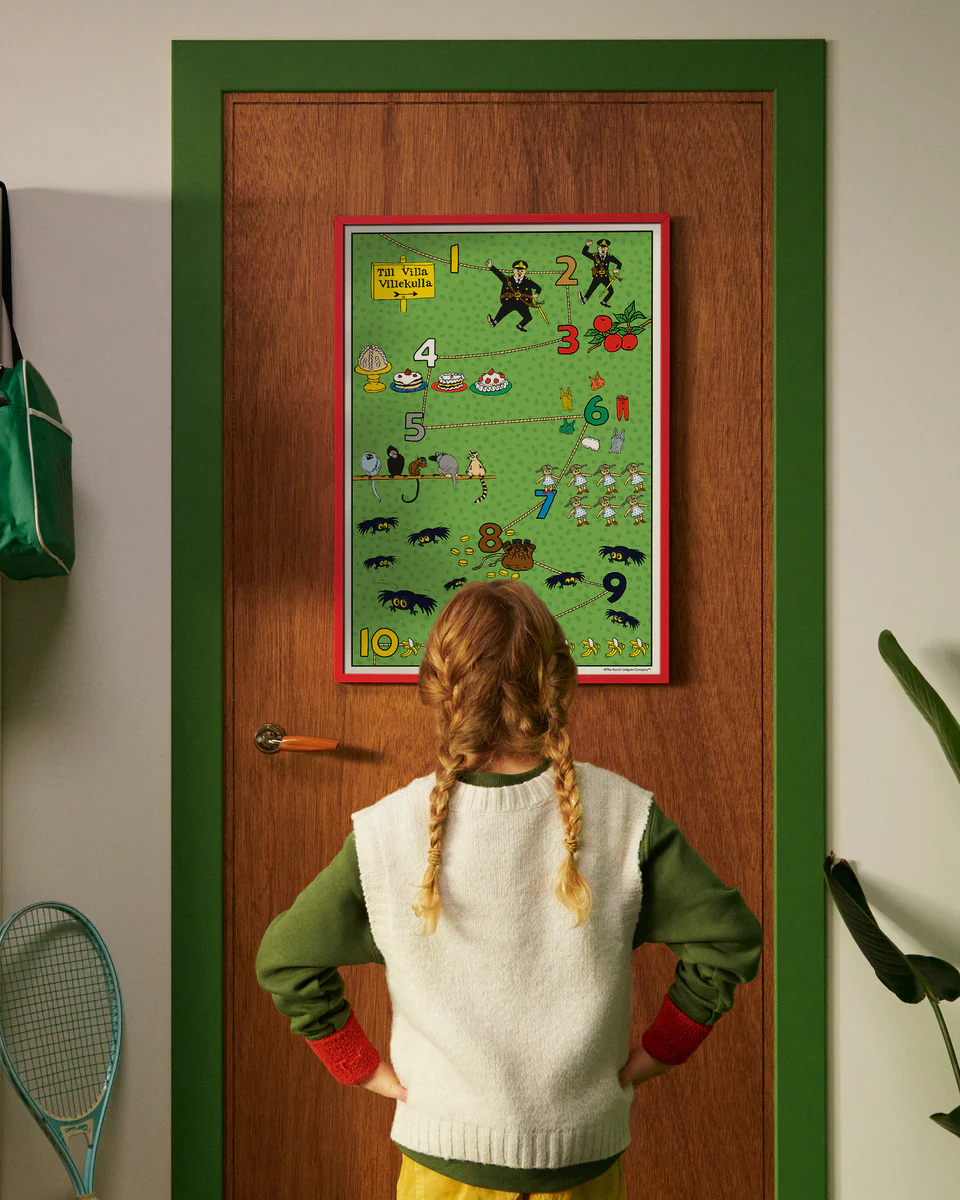 A child looks at a Pippi Longstocking numbers poster hanging on a door.