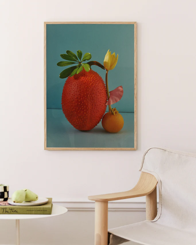 Poster featuring  a stilllife featuring fruits and a yellow tulip against a blue background in a oak frame set in a livingroom