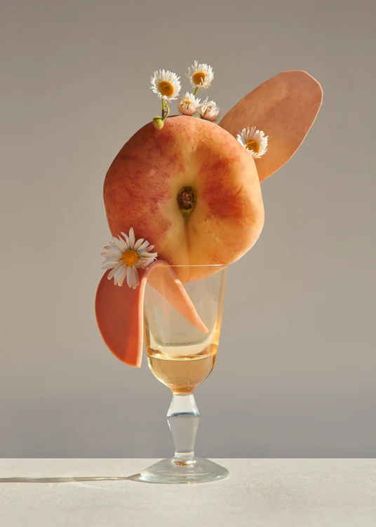 Stilllife photography of a drink adorned with a peach and flowers