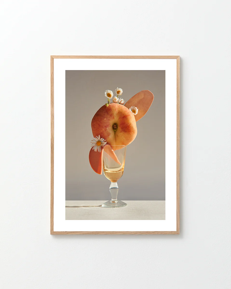 Poster featuring a stilllife photography of a drink adorned with a peach and flowers in a oak frame