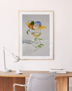 Poster featuring a stilllife photograph featuring a wine glas and on top a piece of papaya and a white flower in a oakframe above a desk