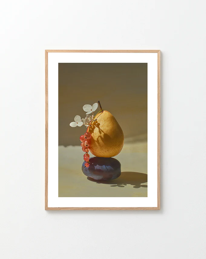 Poster featuring  a stillife photography of a pear balancing on a plum in a oak frame