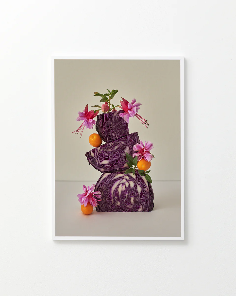 Poster featuring a still life composition of red cabbages balanced on top of each other, adorned with pink flowers, set against a white background in a white frame