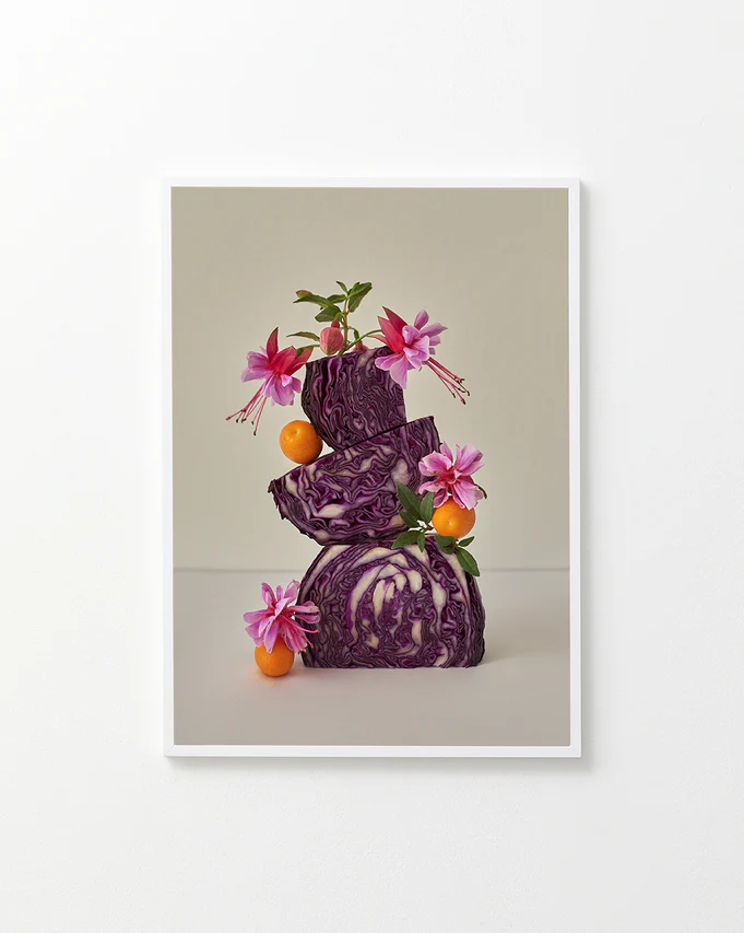 Poster featuring a still life composition of red cabbages balanced on top of each other, adorned with pink flowers, set against a white background in a white frame