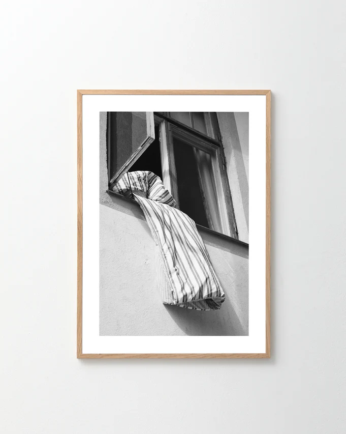 Striped sheets hanging out from an open window.