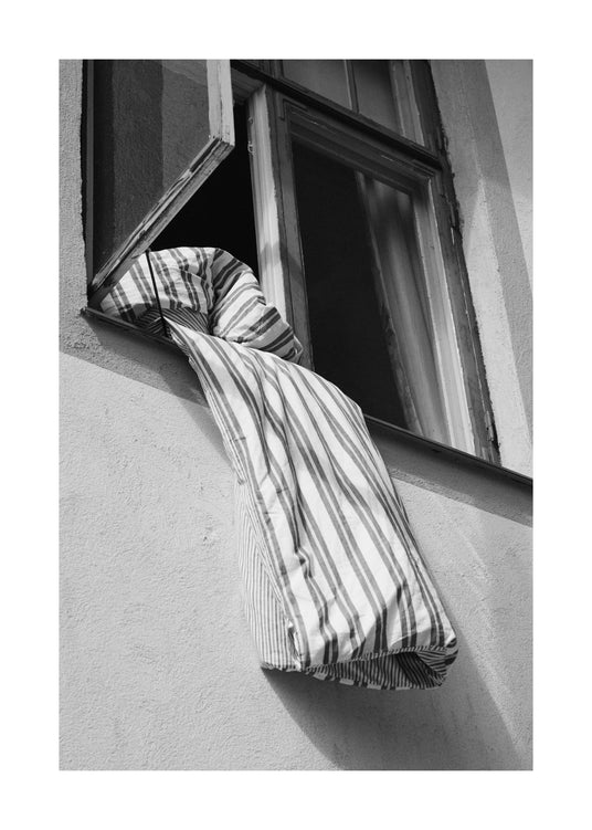 Striped sheets hanging out from an open window.