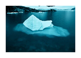 Iceberg floating in a deep blue lake in a cold landscape.