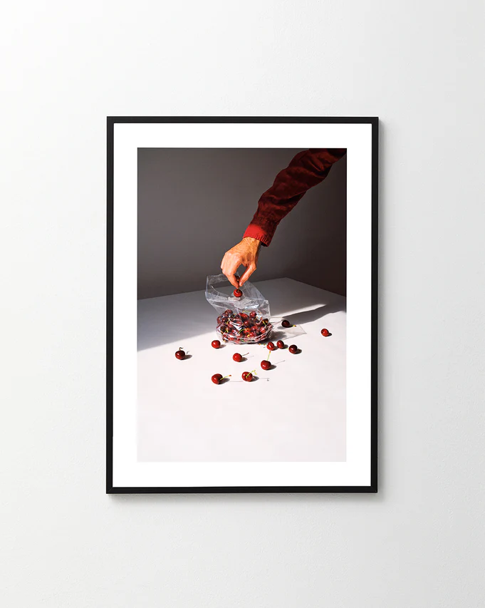 The Summer Treats Poster showcases a hand reaching into a clear plastic bag of cherries on a white surface, with several cherries scattered around, casting shadows in bright light.