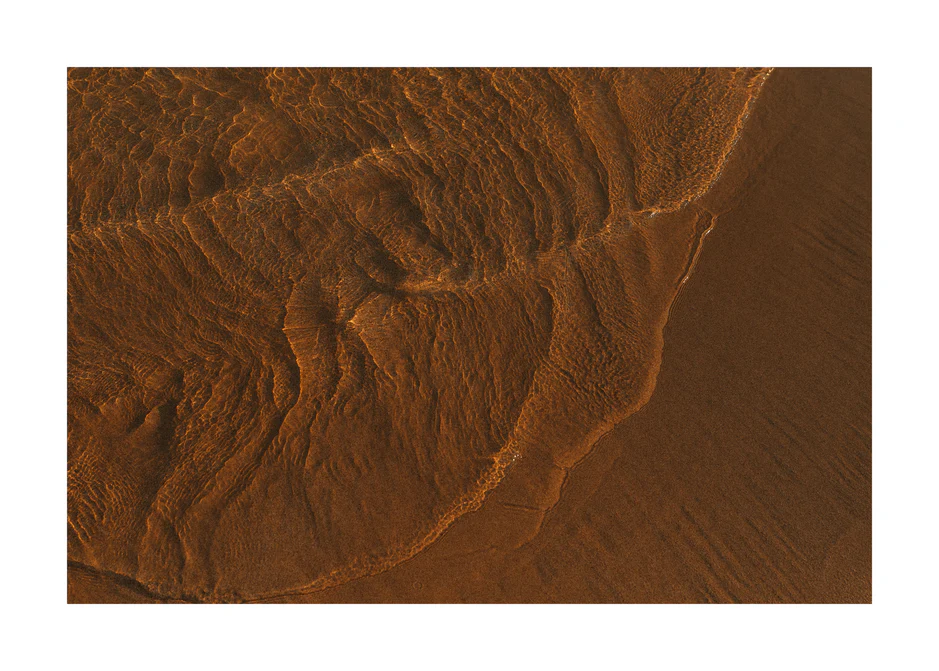 Waves of clear waters softly curling over a sandy shore.